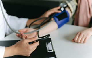 Medical professional checks a patient’s blood pressure using a cuff and stethoscope (close-up).