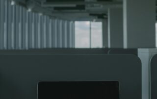 Laptop on desk in a dim office; screen shows the words 'CYBER SECURITY' in red font.