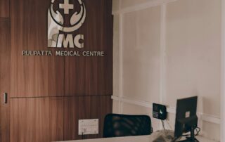 Reception desk at Pulpatta Medical Centre with the IMC logo on a wood-paneled wall.