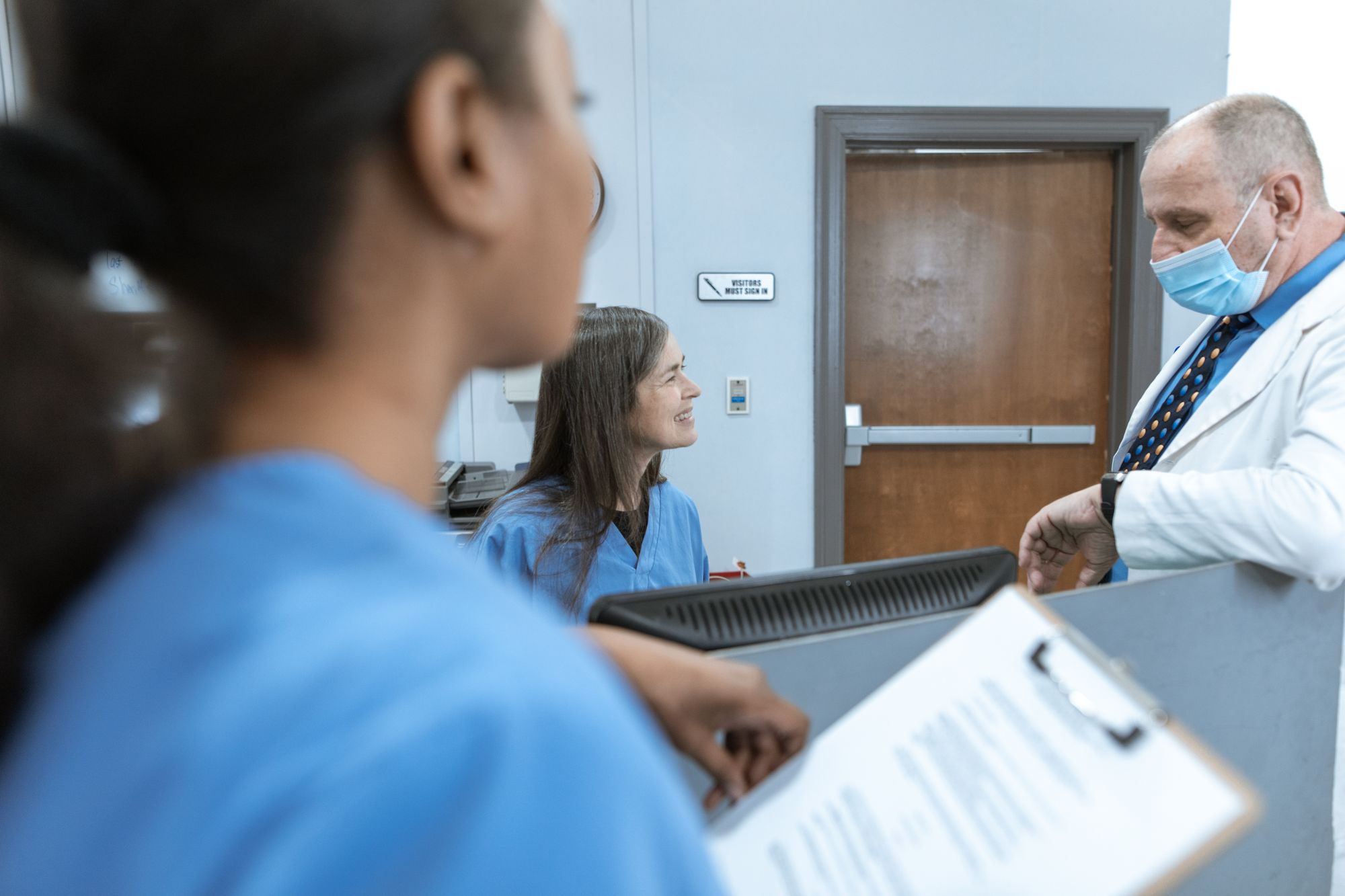 Healthcare staff in discussion together at a clinic reception area