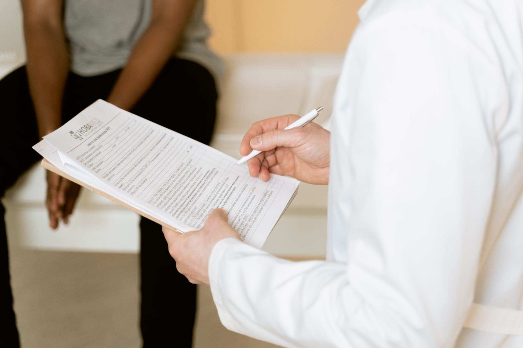 A clinician completing a patient intake form on a clipboard