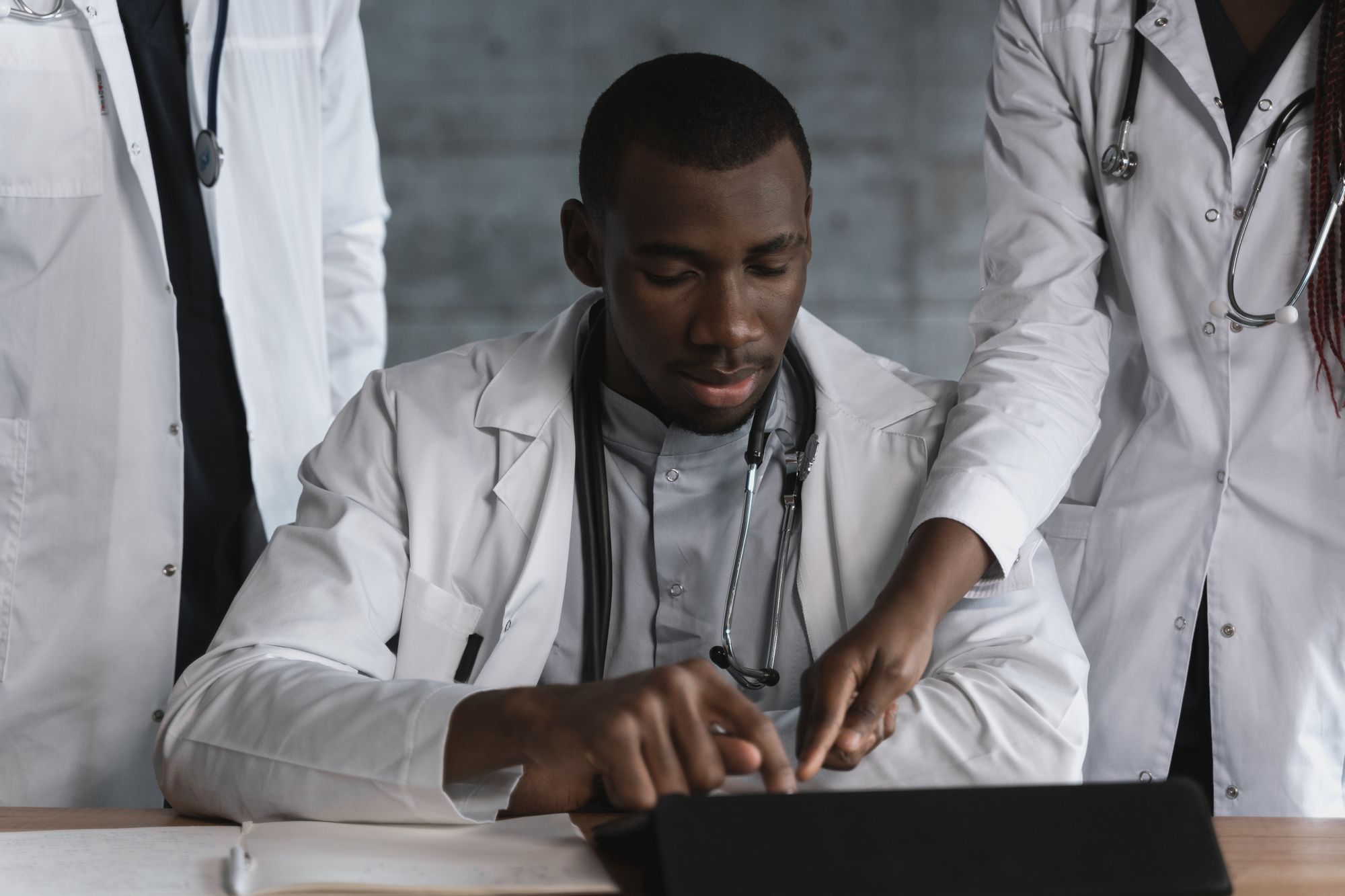 A clinician working at a laptop while two colleagues review the screen
