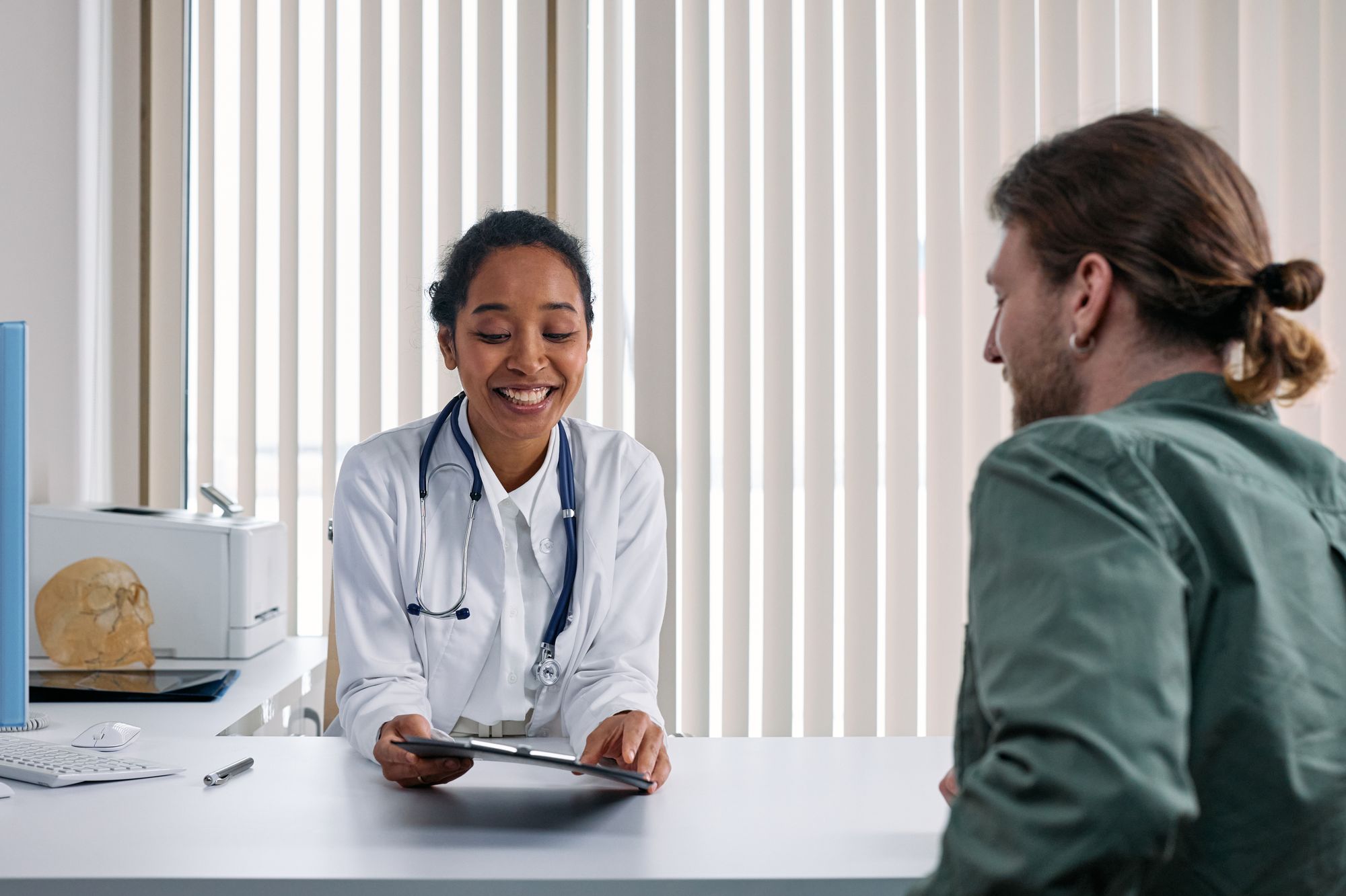 A doctor talking with a patient across a consulting room desk