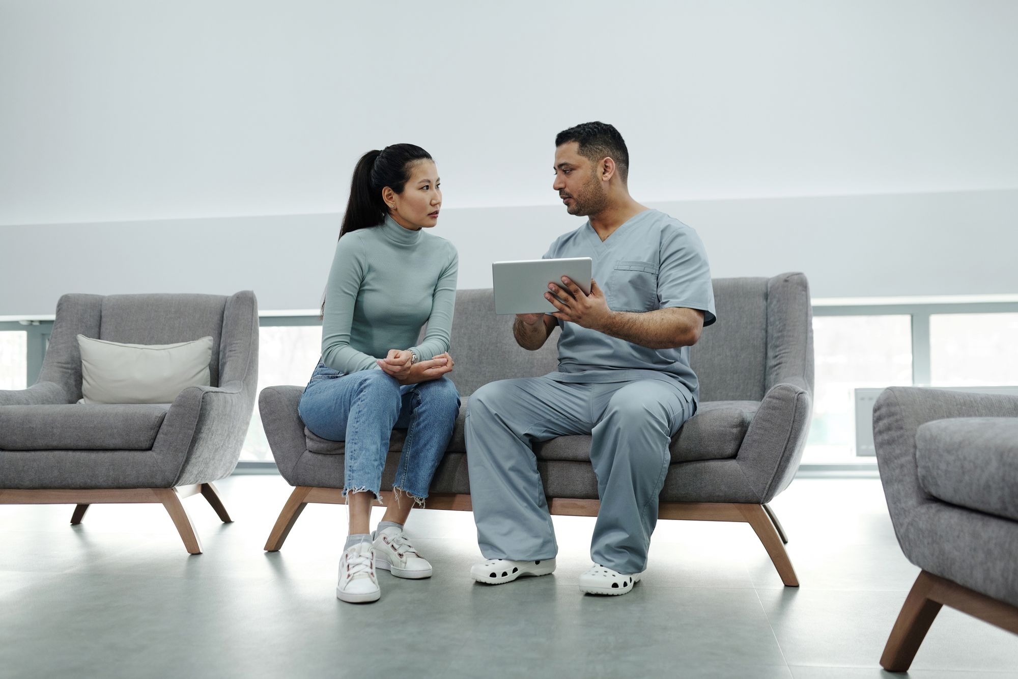 A clinician consulting a patient while holding a tablet