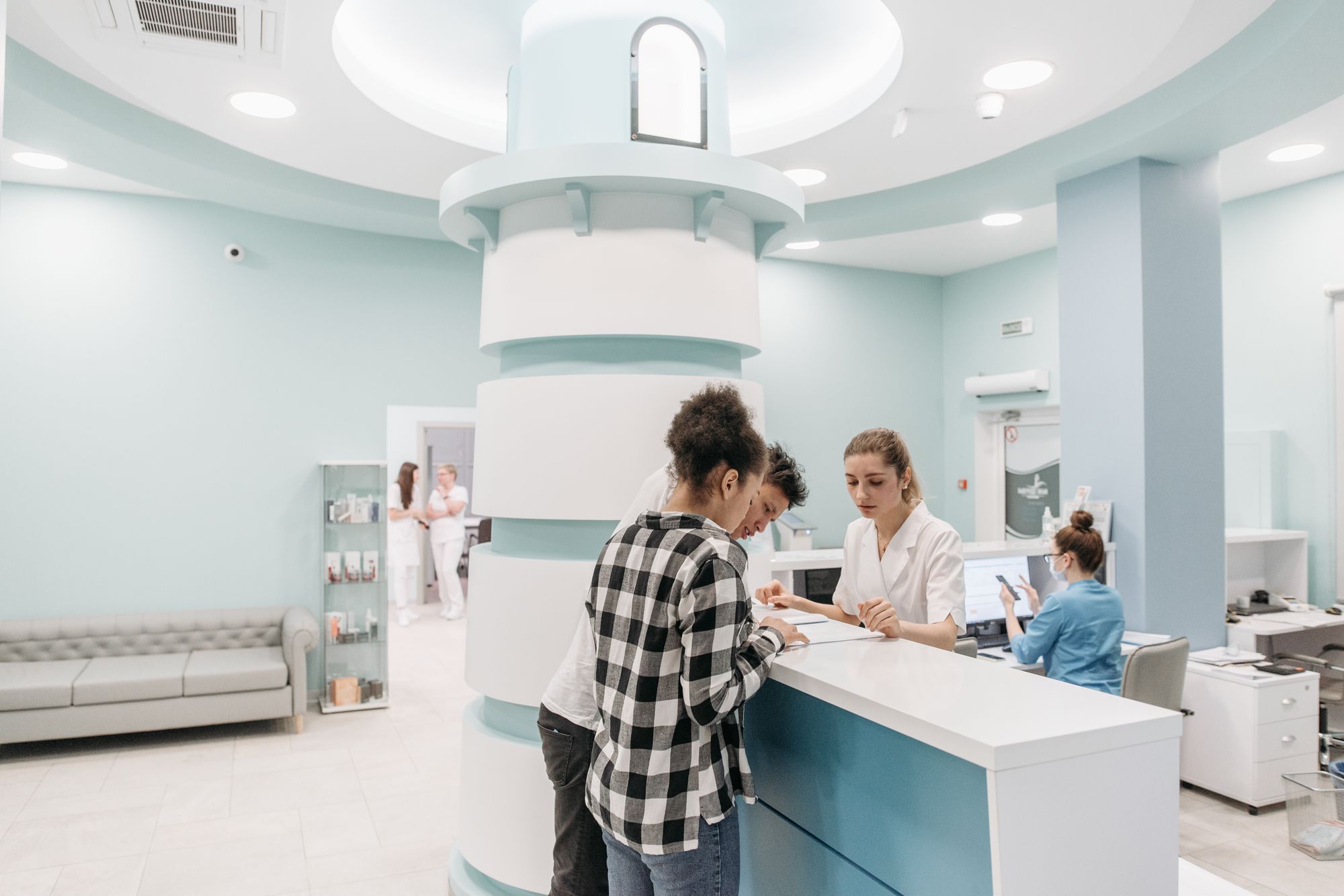 Clinic reception staff checking in patients at a bright front desk