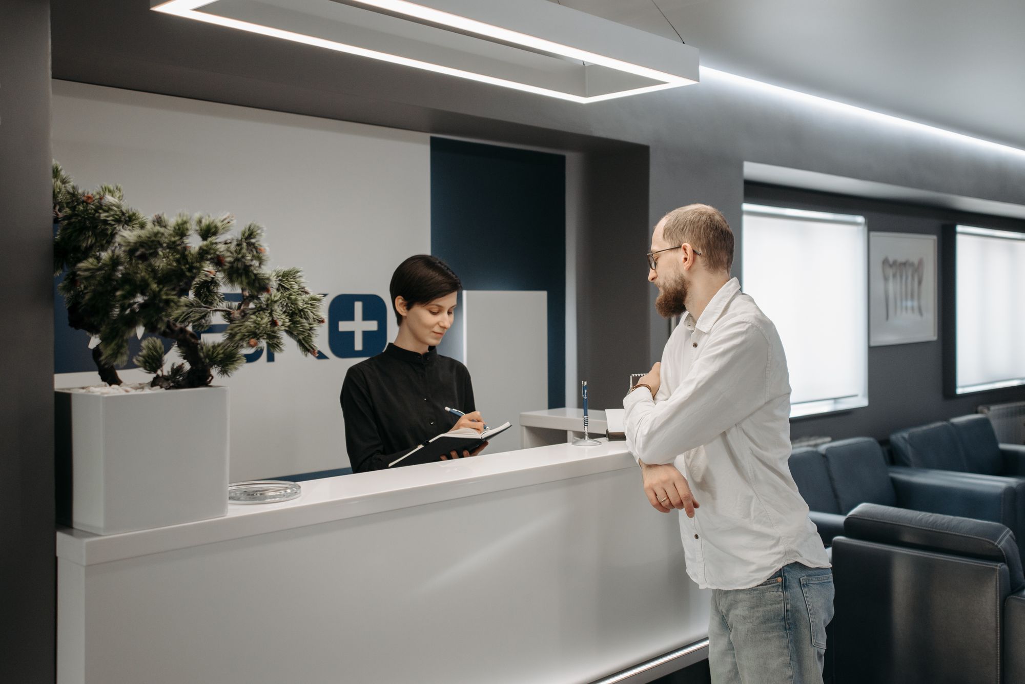 A patient being helped by a receptionist at a clinic front desk