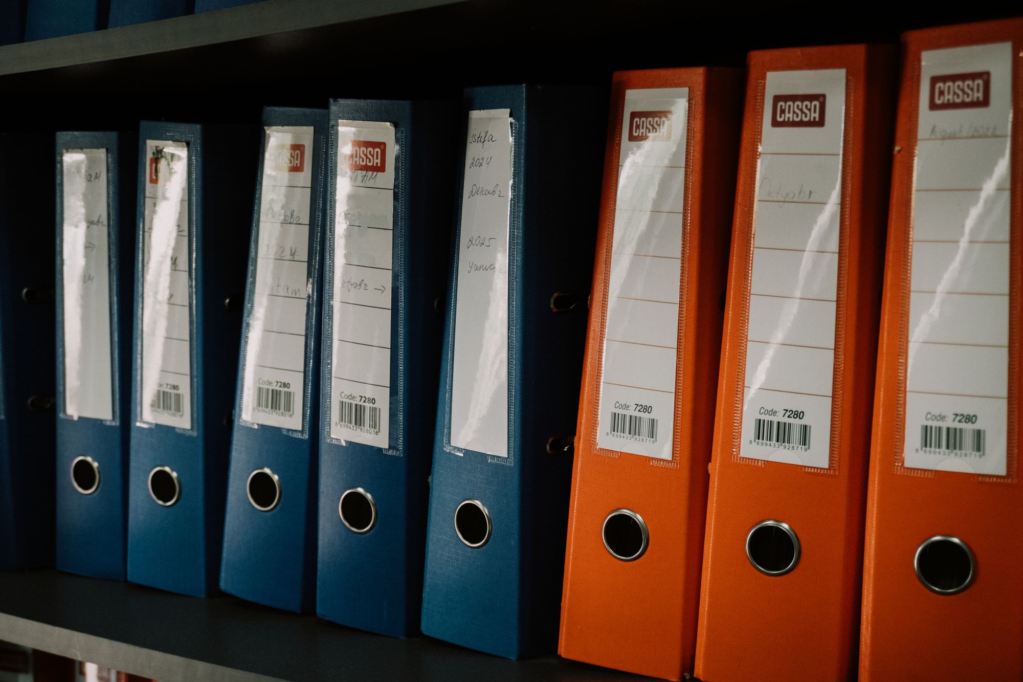 Rows of labelled ring binders arranged on an office shelf