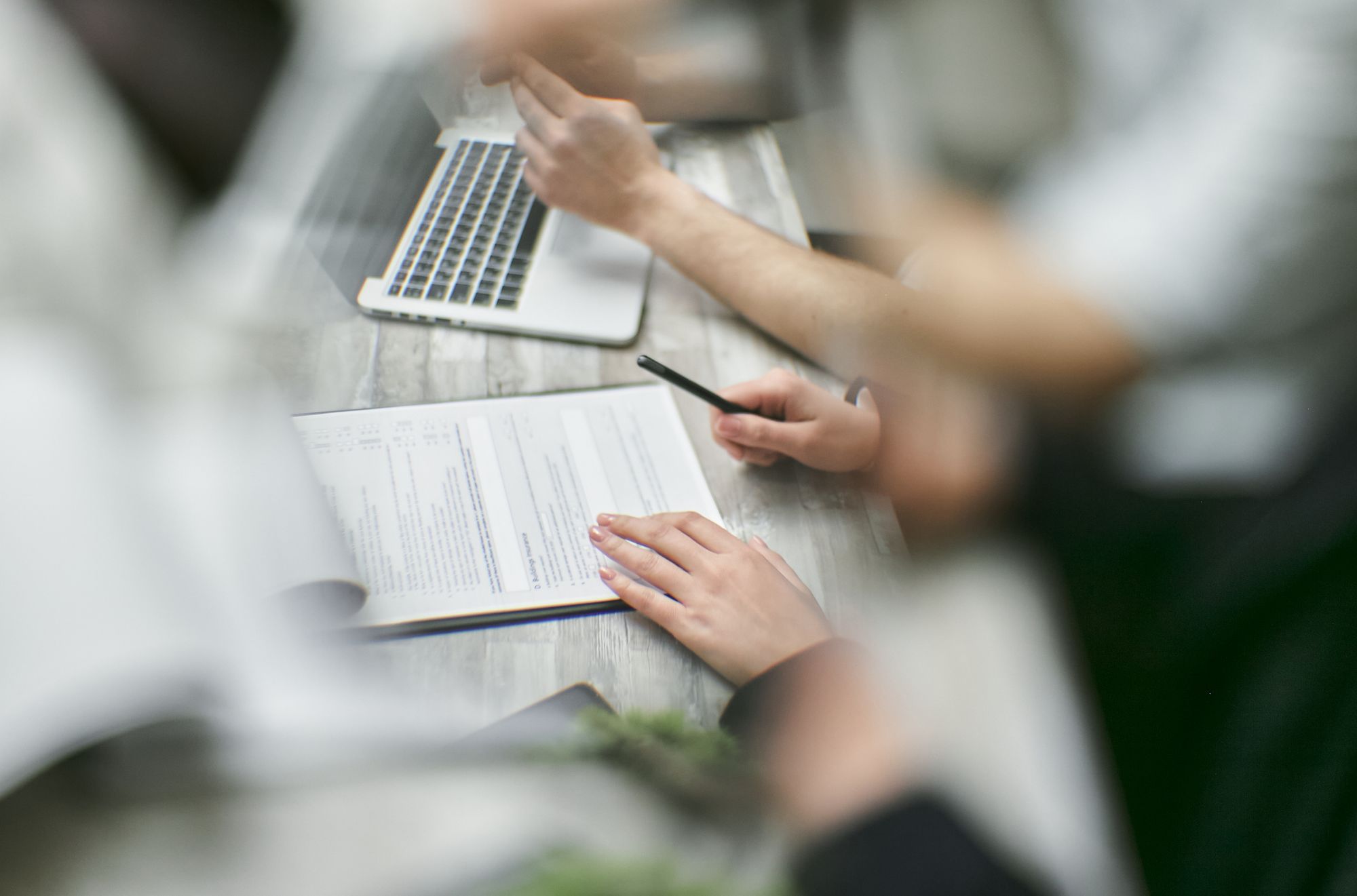 A team gathered around documents and a laptop in an office