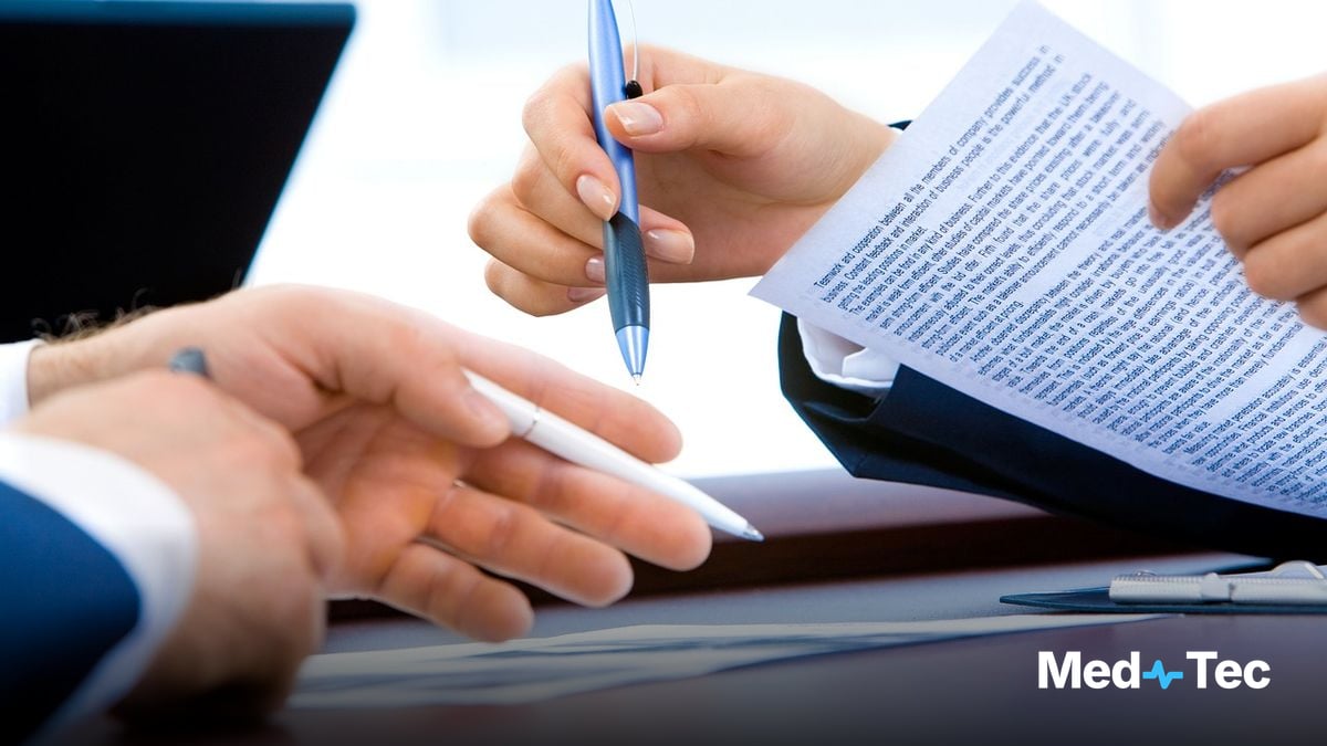 A practice manager and clinician discussing documentation at a clinic front desk